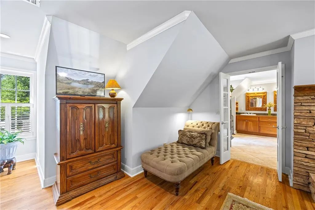 Sitting room with vaulted ceiling, baseboards, light wood-style floors, and crown molding