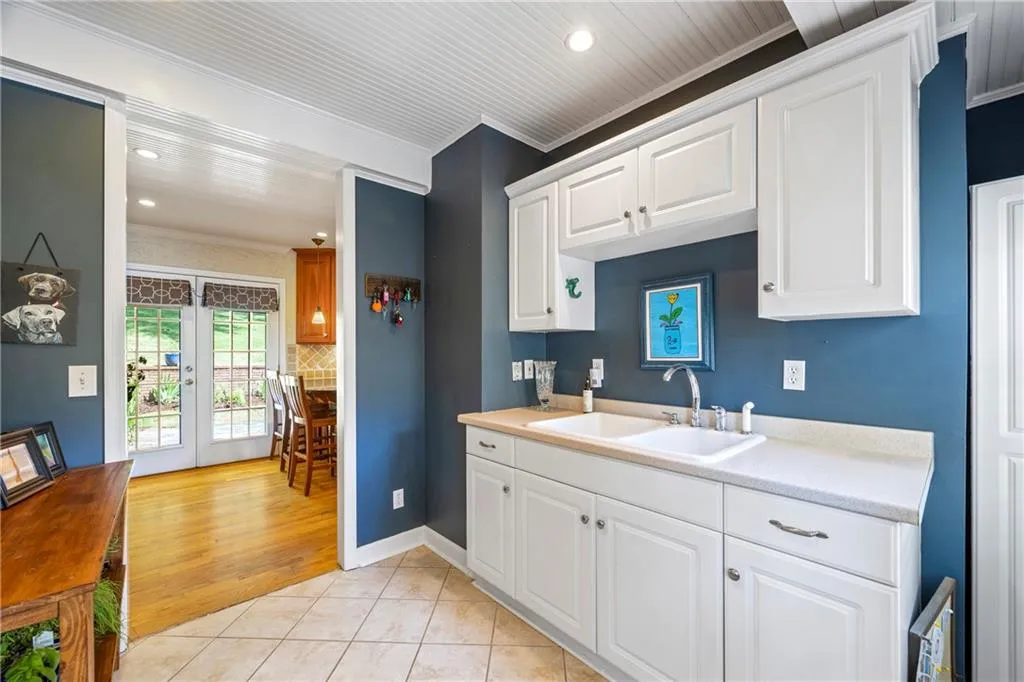 Kitchen featuring light countertops, ornamental molding, french doors, a sink, and white cabinetry