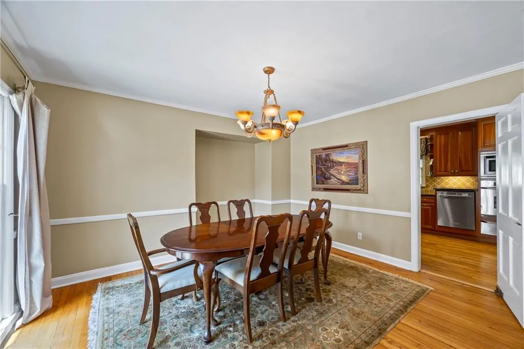 Dining space with a chandelier, light wood finished floors, baseboards, and ornamental molding