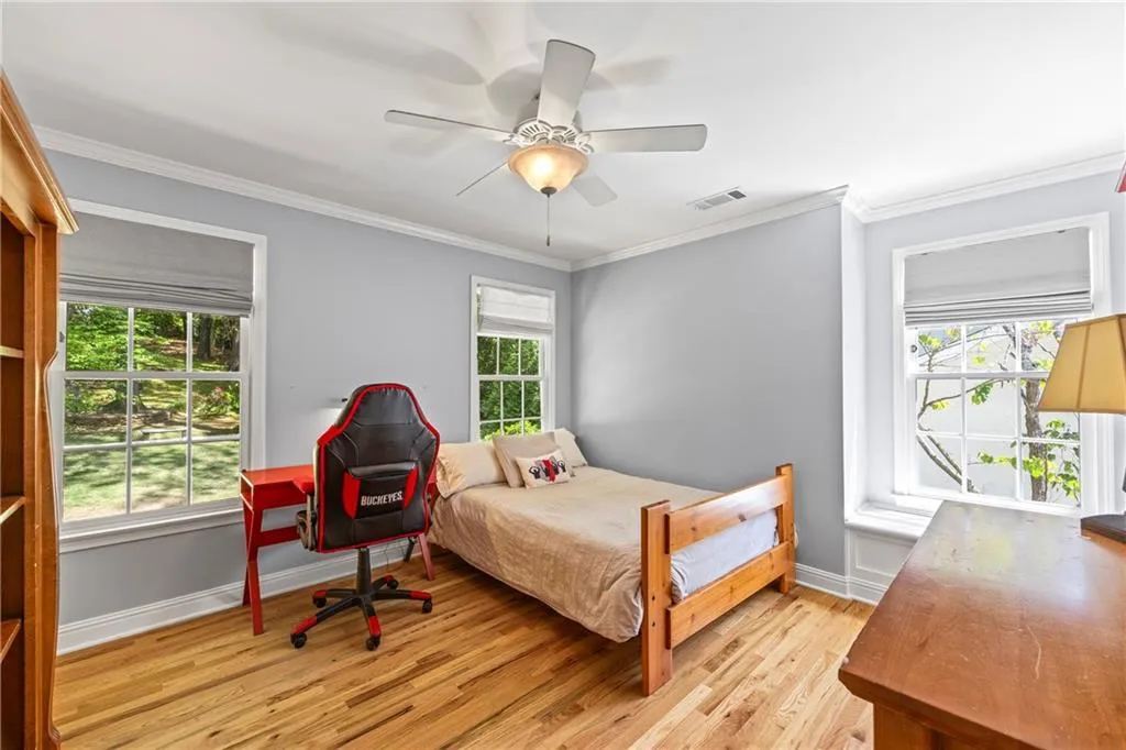Bedroom with crown molding, ceiling fan, light wood finished floors, baseboards, and visible vents