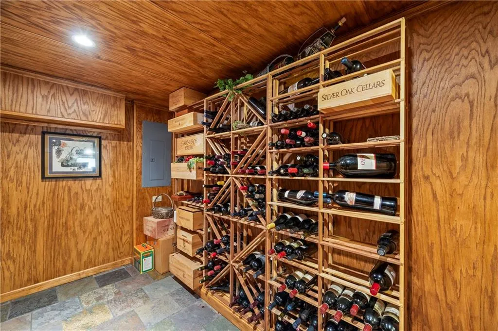 Wine cellar with stone finish floor, wooden walls, wooden ceiling, electric panel, and baseboards