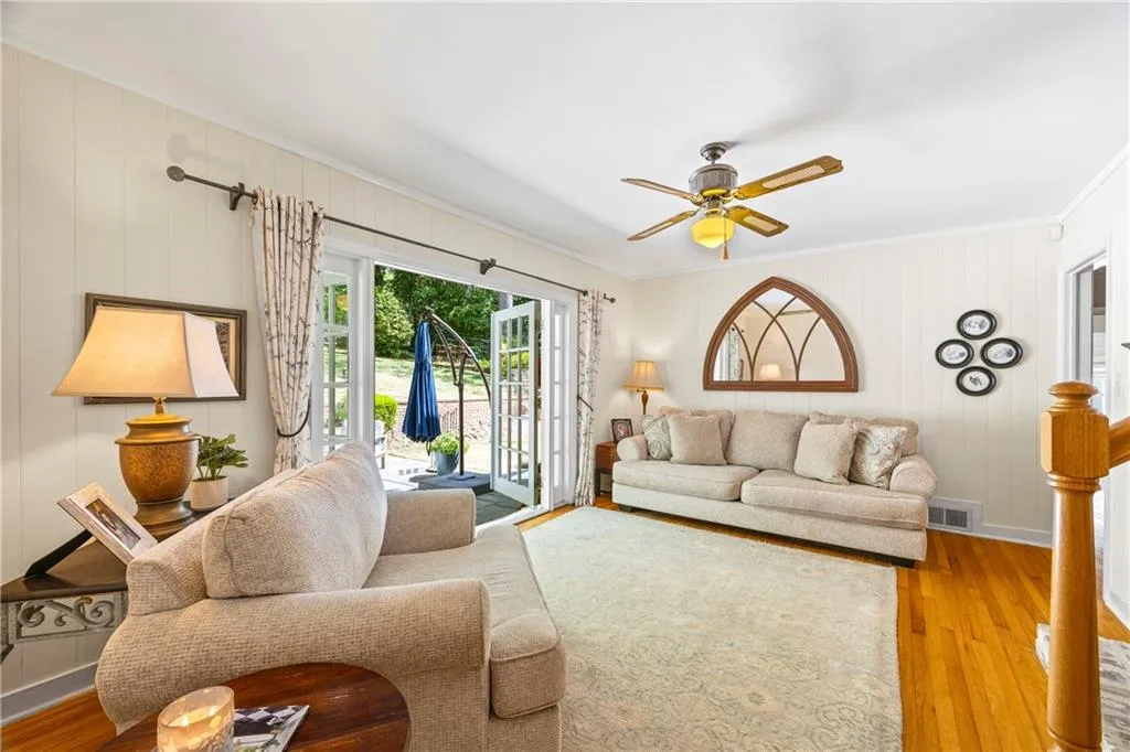 Living area featuring a ceiling fan, crown molding, and light wood finished floors