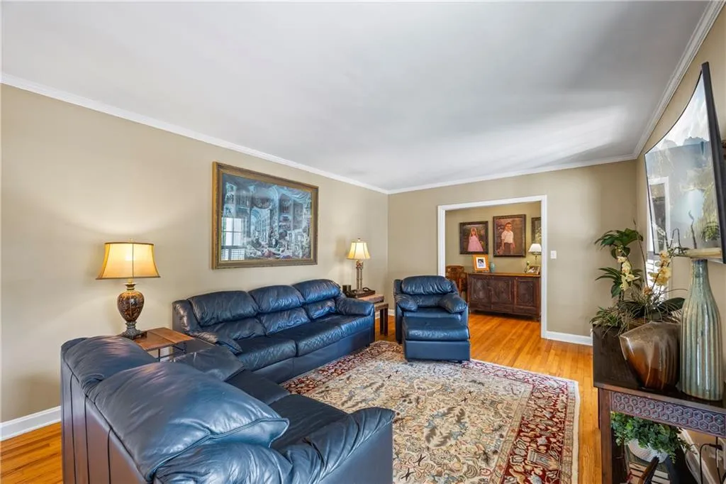 Living area with baseboards, wood finished floors, and ornamental molding