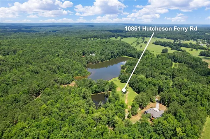Expansive aerial landscape featuring a large body of water, extensive wooded areas, and open fields