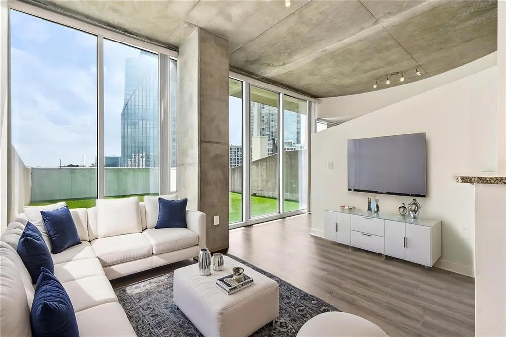 Floor-to-ceiling windows, concrete structural elements, exposed concrete ceiling, recessed lighting, and wood-finish flooring