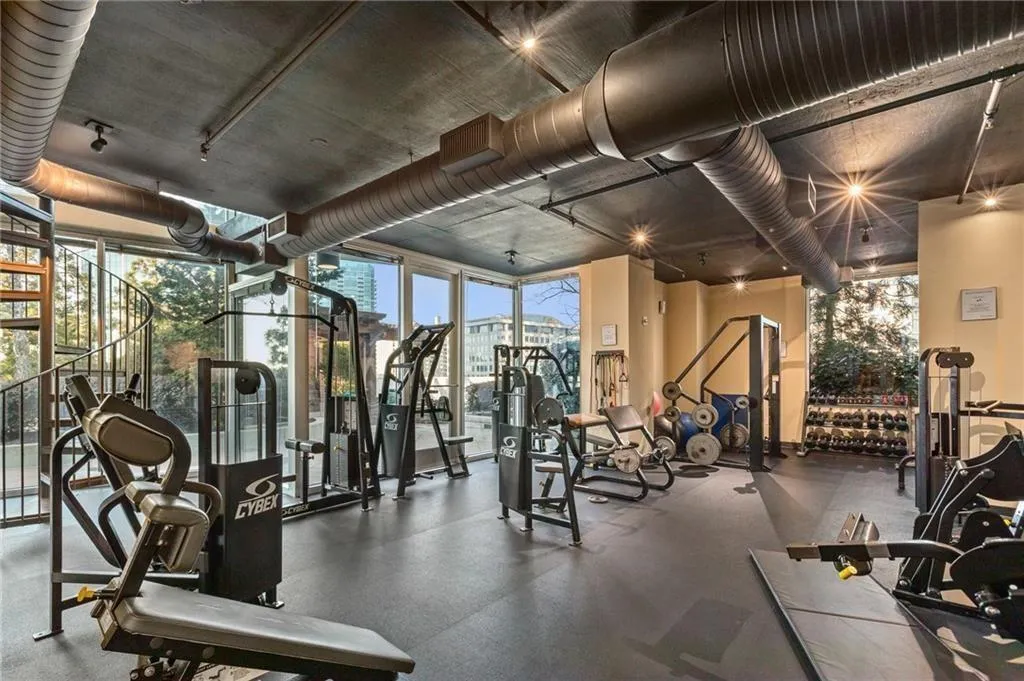 Fitness center with floor-to-ceiling windows, exposed ductwork, recessed lighting, and a spiral staircase
