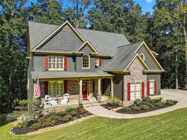 Traditional style home featuring a stone and siding exterior, multiple gables, and red shutters