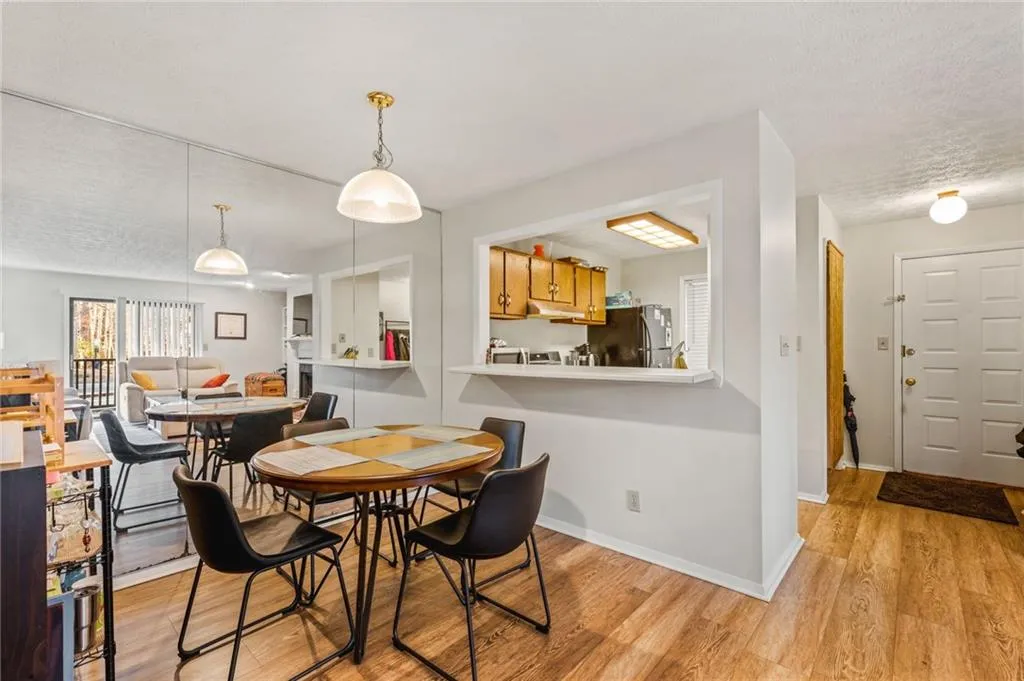 Dining space with light wood finished floors, a textured ceiling, and baseboards