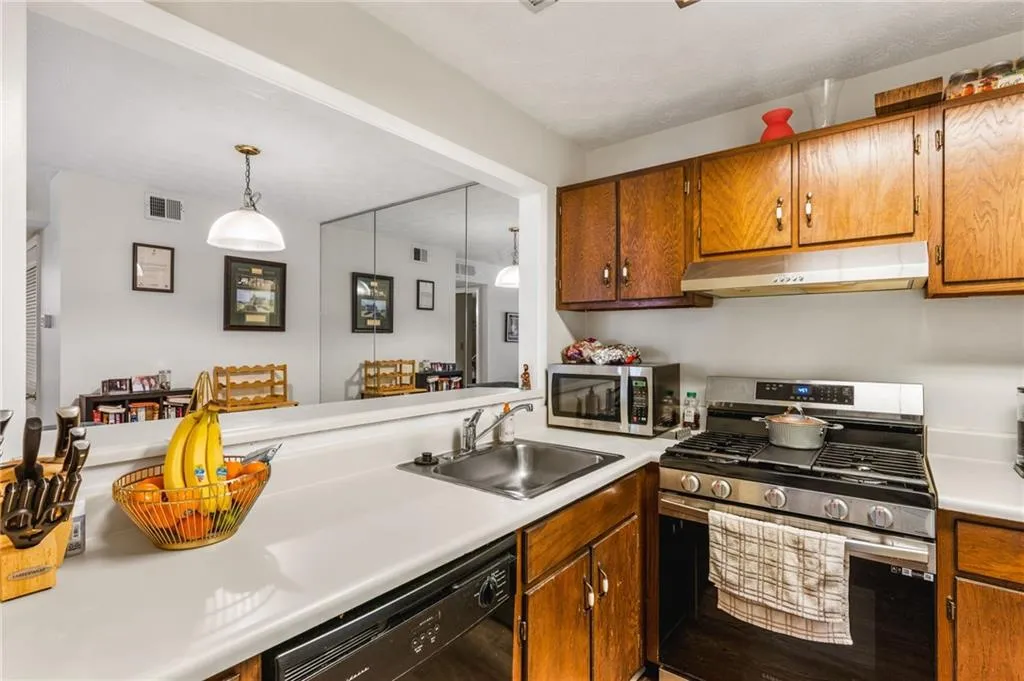 Kitchen with visible vents, under cabinet range hood, a sink, appliances with stainless steel finishes, and light countertops