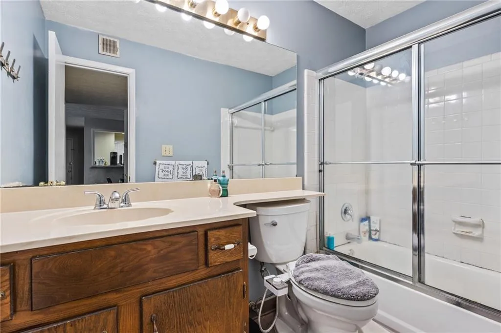 Full bath featuring visible vents, vanity, toilet, and shower / bath combination with glass door