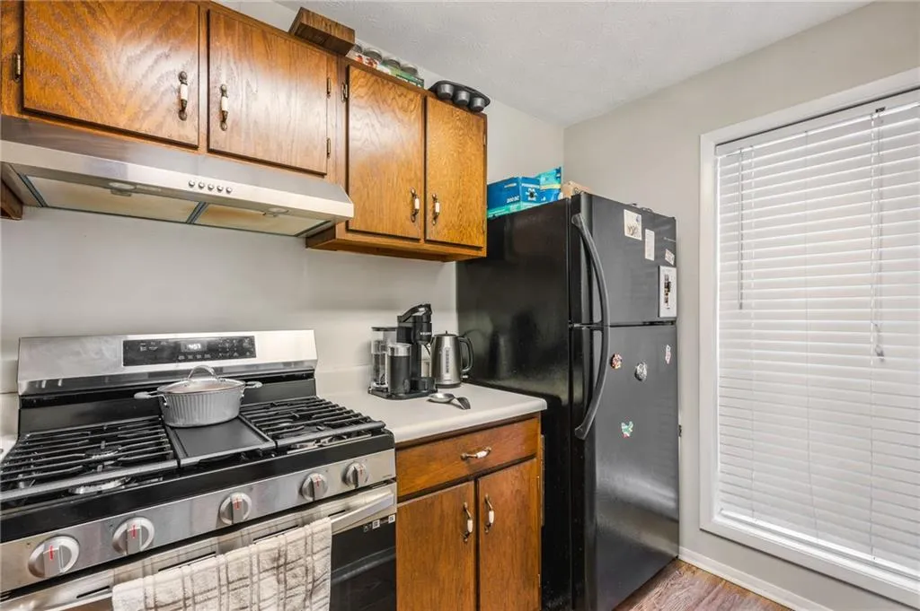 Kitchen featuring freestanding refrigerator, stainless steel range with gas stovetop, brown cabinets, and under cabinet range hood
