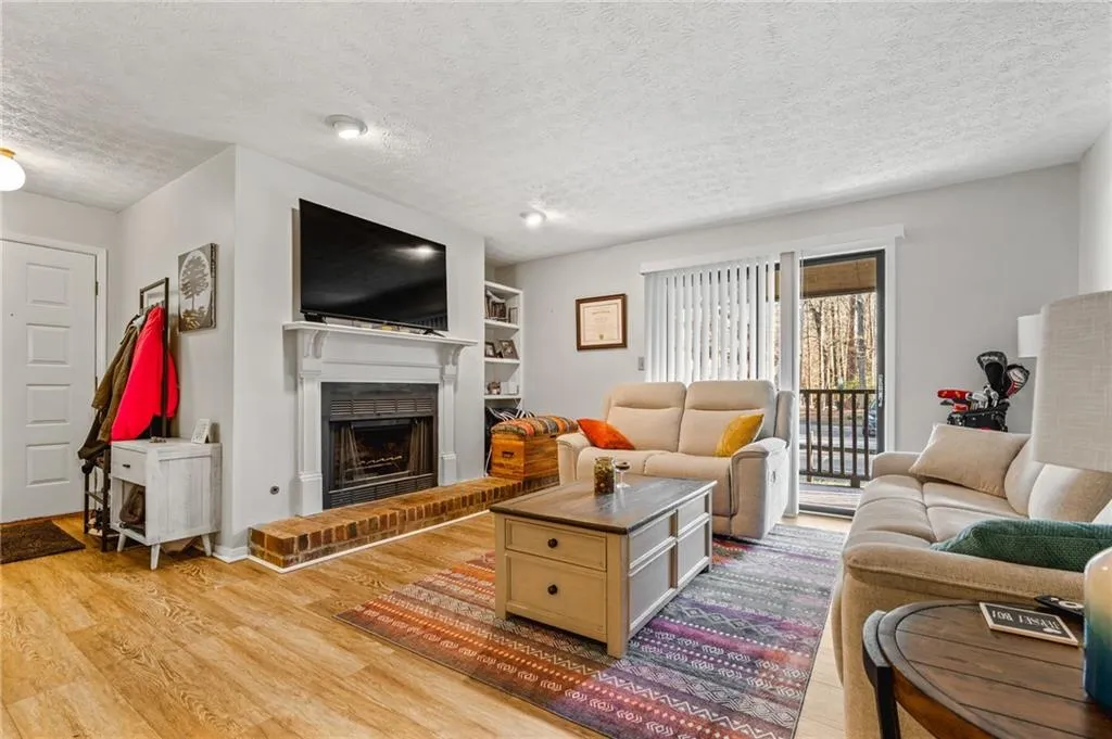 Living room featuring a fireplace, a textured ceiling, and light wood-type flooring