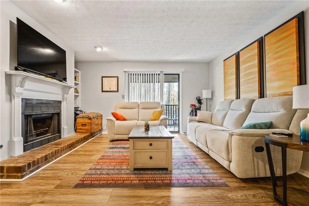 Living area featuring a textured ceiling, light wood-style flooring, and a fireplace