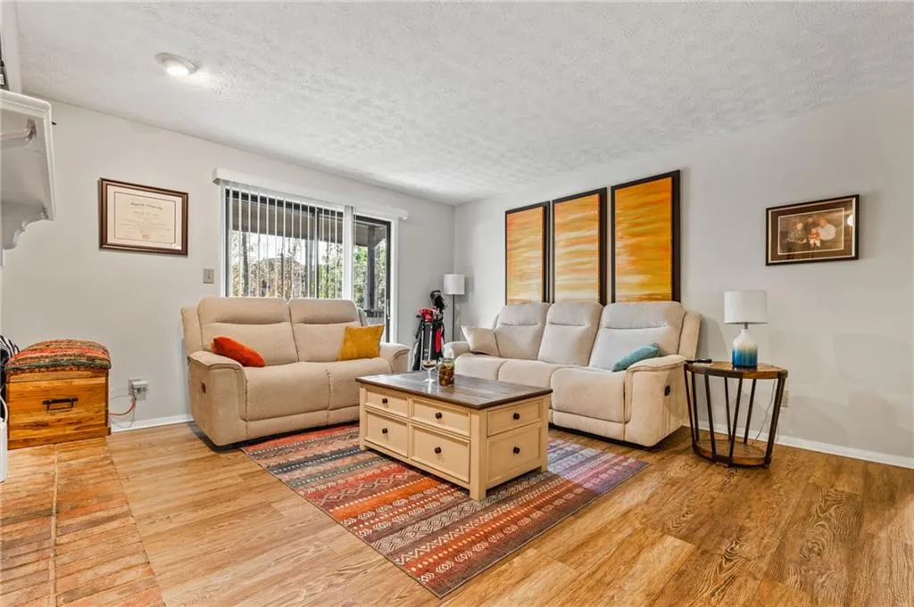 Living area featuring baseboards, light wood-type flooring, and a textured ceiling