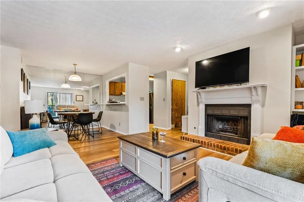 Living area featuring a brick fireplace, wood finished floors, and a textured ceiling
