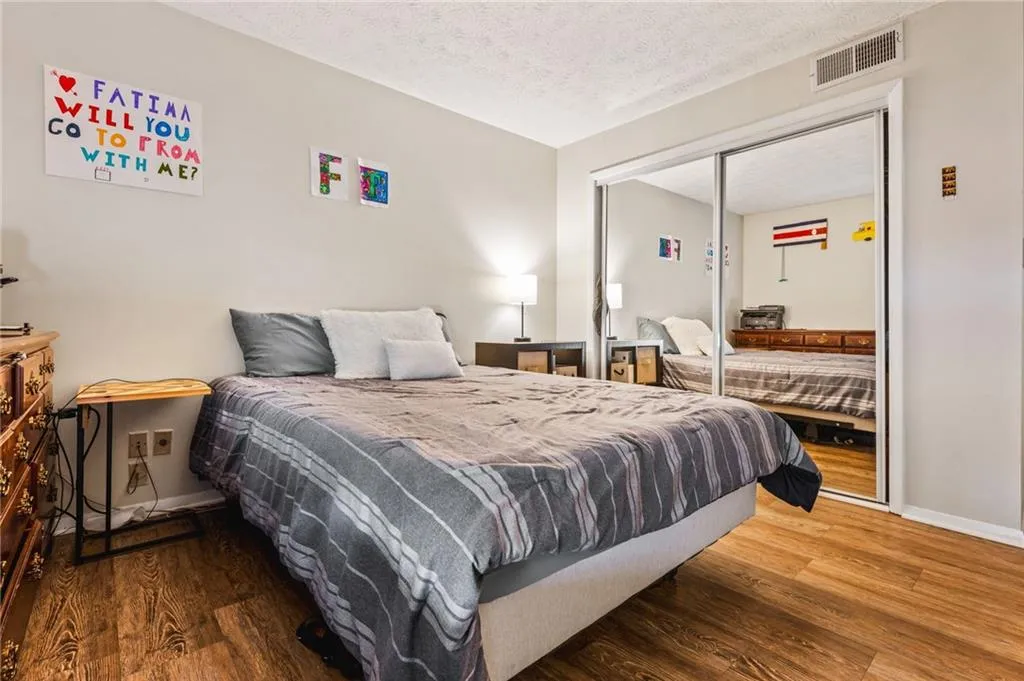 Bedroom featuring visible vents, baseboards, a textured ceiling, and wood finished floors