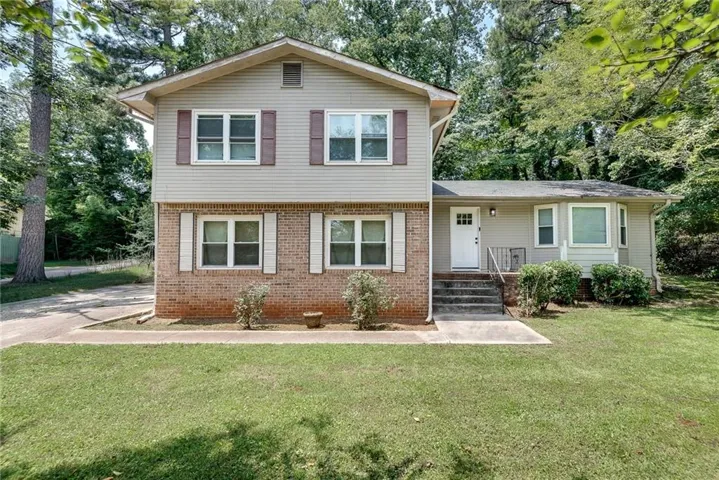 Two-story residence featuring a brick and siding facade, an inviting front entry with steps, a bay window, and a concrete driveway