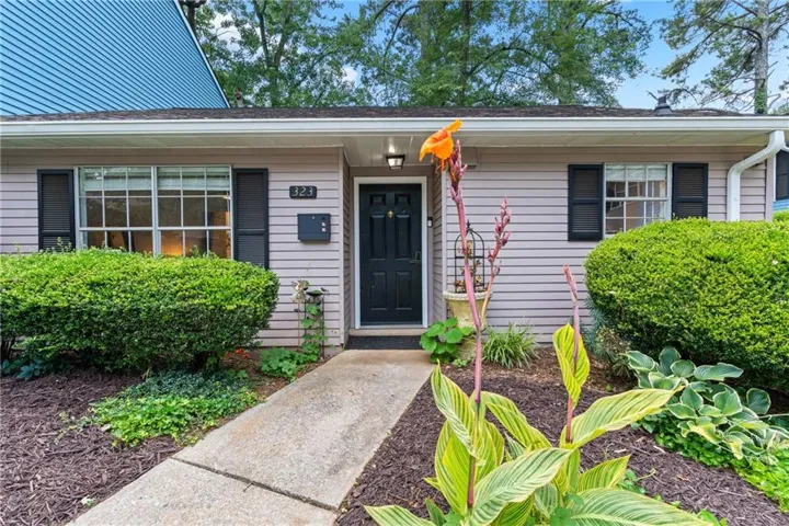 Horizontal siding exterior with a dark entry door, front porch lighting, and a prominent front window with dark shutters