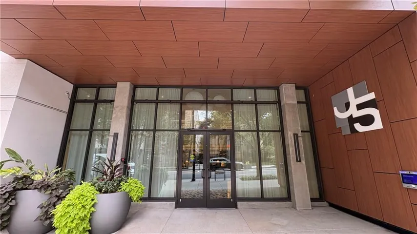 Building entrance with wood-finish paneling, large fixed windows, and a glass-paneled double door