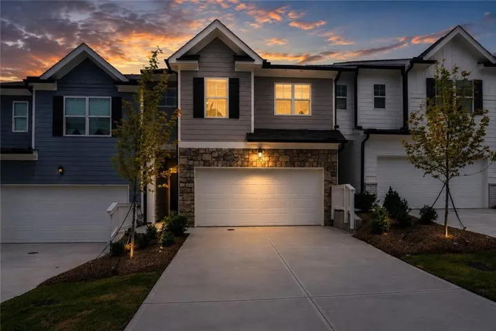 Modern townhouse exterior with stone facade, individual garage, and paved driveway