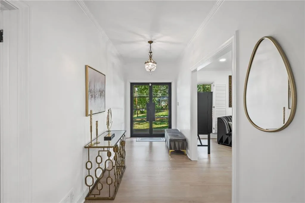 Hallway with ornamental molding, light wood-type flooring, a chandelier, and french doors