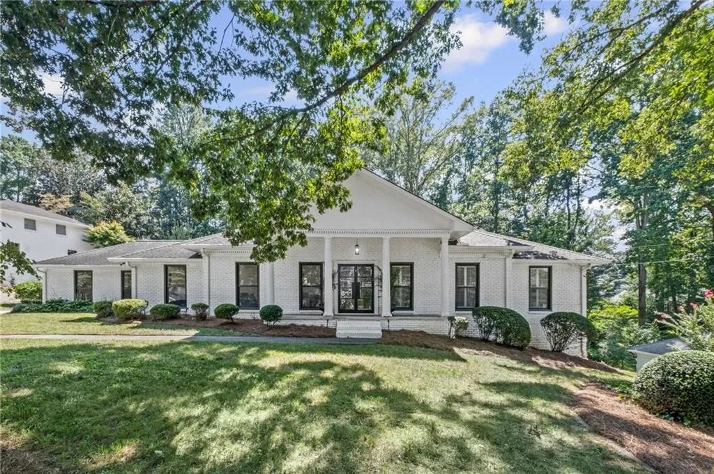 Greek revival inspired property featuring covered porch, a front lawn, and brick siding