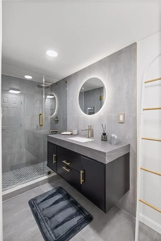 Bathroom with vanity, a shower stall, tile walls, and recessed lighting