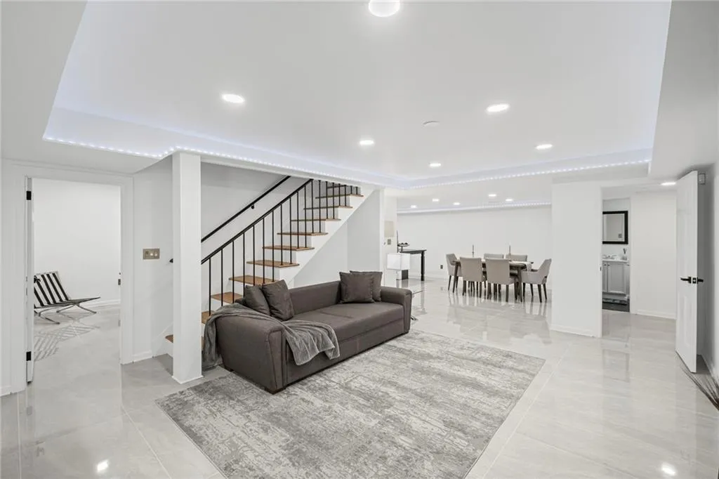 Living area with recessed lighting, a raised ceiling, and stairway