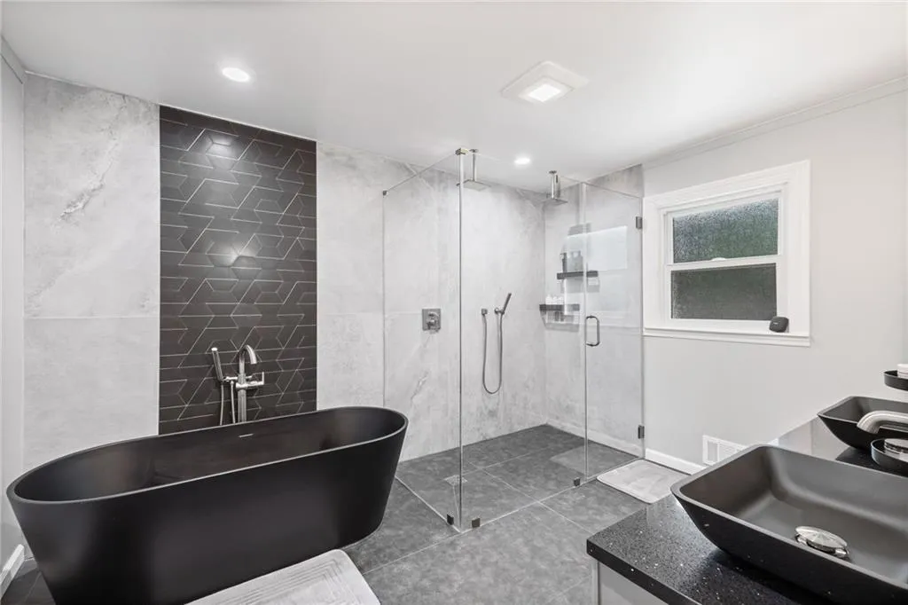 Bathroom featuring tile walls, a freestanding tub, vanity, a stall shower, and tile patterned floors