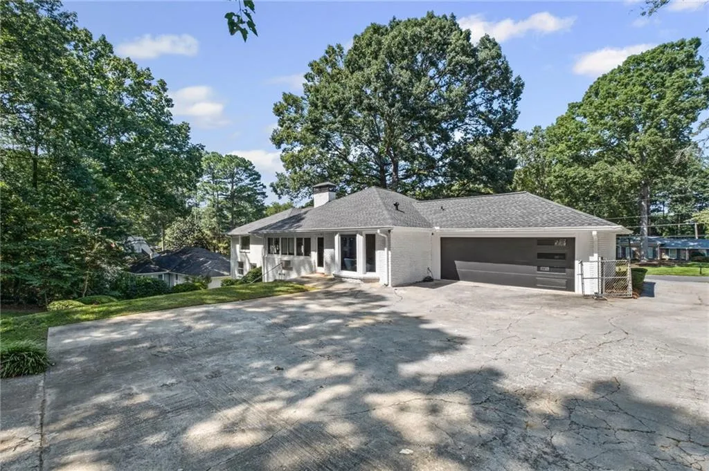 View of front of home featuring driveway, a chimney, brick siding, a garage, and a shingled roof