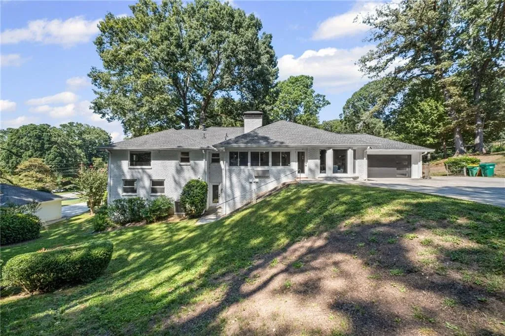 Ranch-style house featuring a chimney, driveway, a front yard, and brick siding