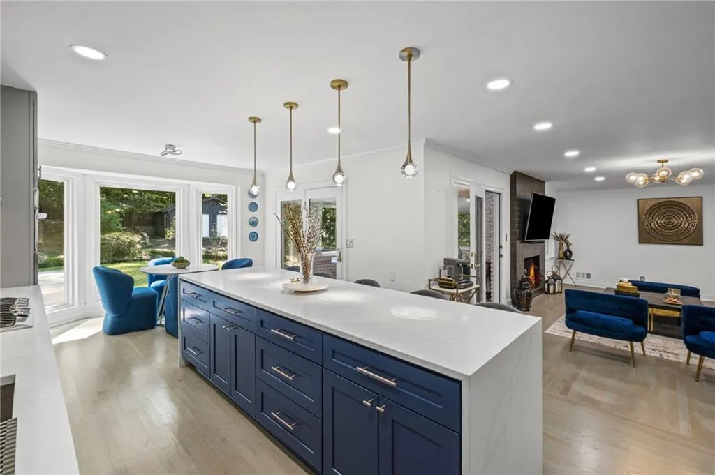 Kitchen featuring blue cabinetry, a fireplace, recessed lighting, decorative light fixtures, and a center island