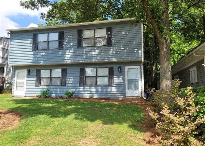 Two-story exterior with horizontal siding, multiple windows, and two entry doors