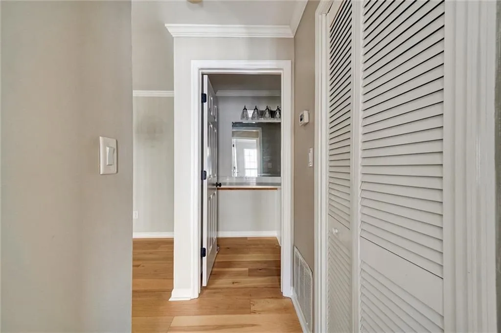 Corridor featuring light wood-style floors and crown molding Corridor featuring light wood-style floors and crown molding