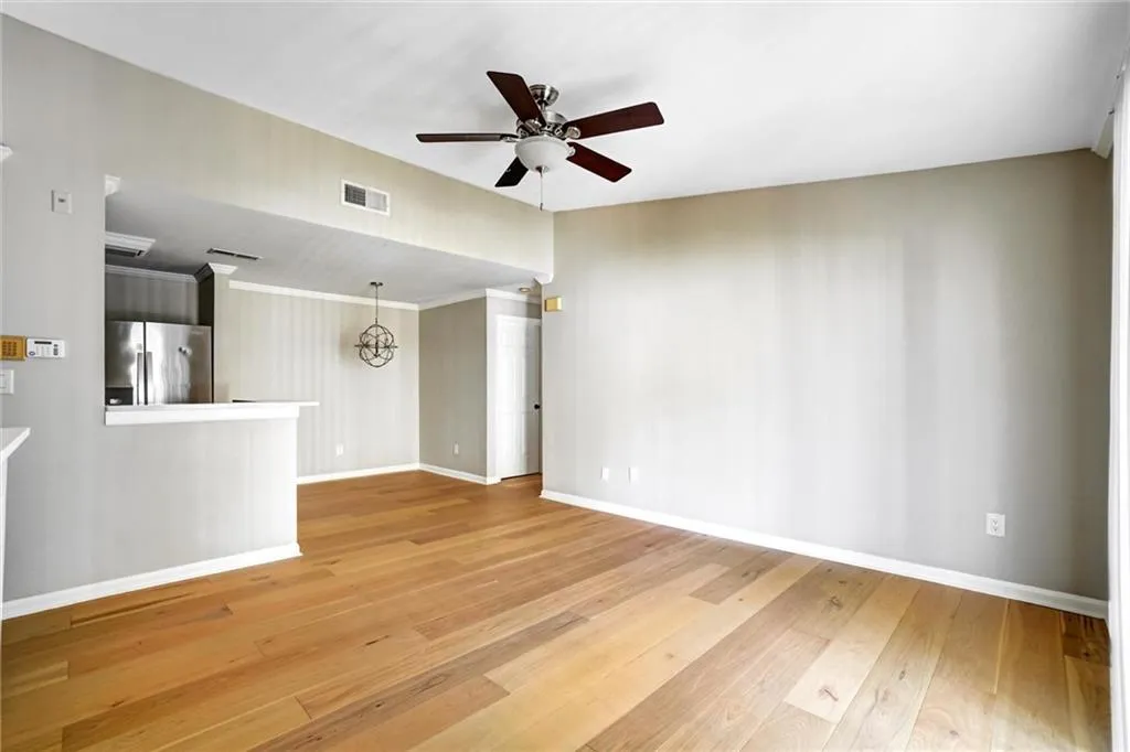 Unfurnished living room with light wood-style flooring, a chandelier, a ceiling fan, and crown molding Unfurnished living room with light wood-style flooring, a chandelier, a ceiling fan, and crown molding