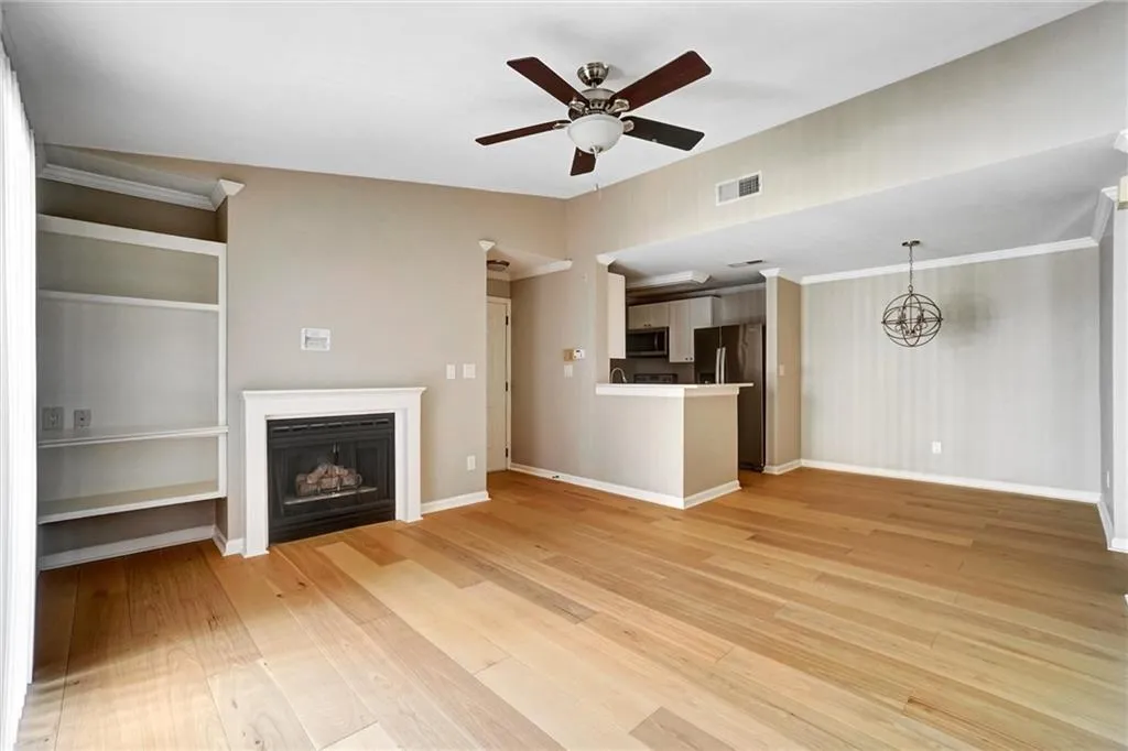 Unfurnished living room with a fireplace, light wood-style flooring, ceiling fan, and crown molding Unfurnished living room with a fireplace, light wood-style flooring, ceiling fan, and crown molding