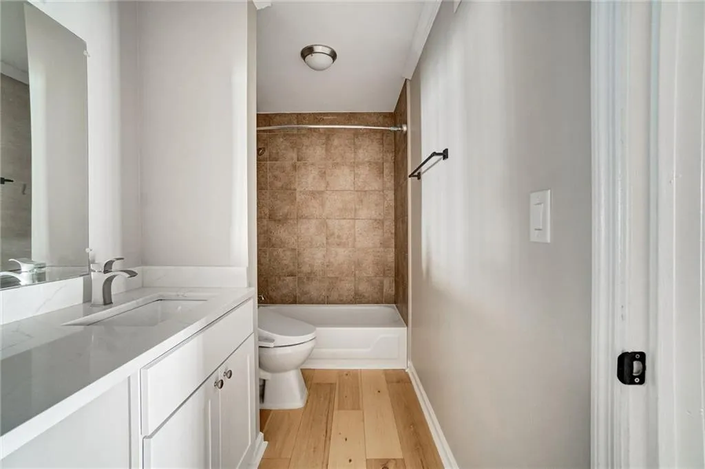 Full bathroom featuring vanity, light wood finished floors, and shower / bath combination Full bathroom featuring vanity, light wood finished floors, and shower / bath combination