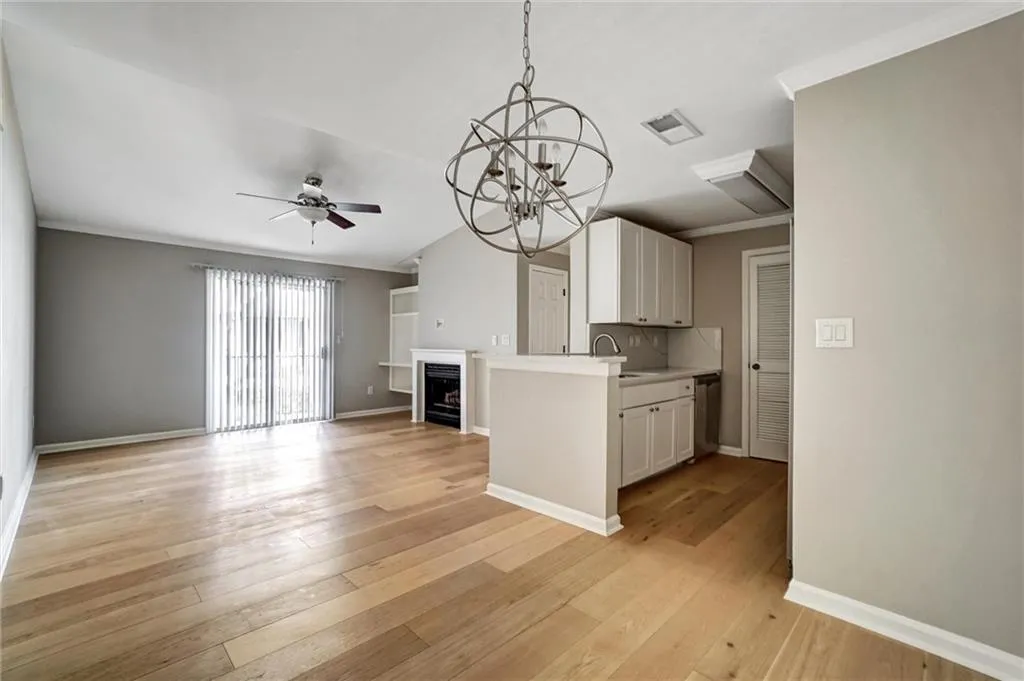Kitchen with white cabinetry, a chandelier, light countertops, a fireplace, and a ceiling fan Kitchen with white cabinetry, a chandelier, light countertops, a fireplace, and a ceiling fan