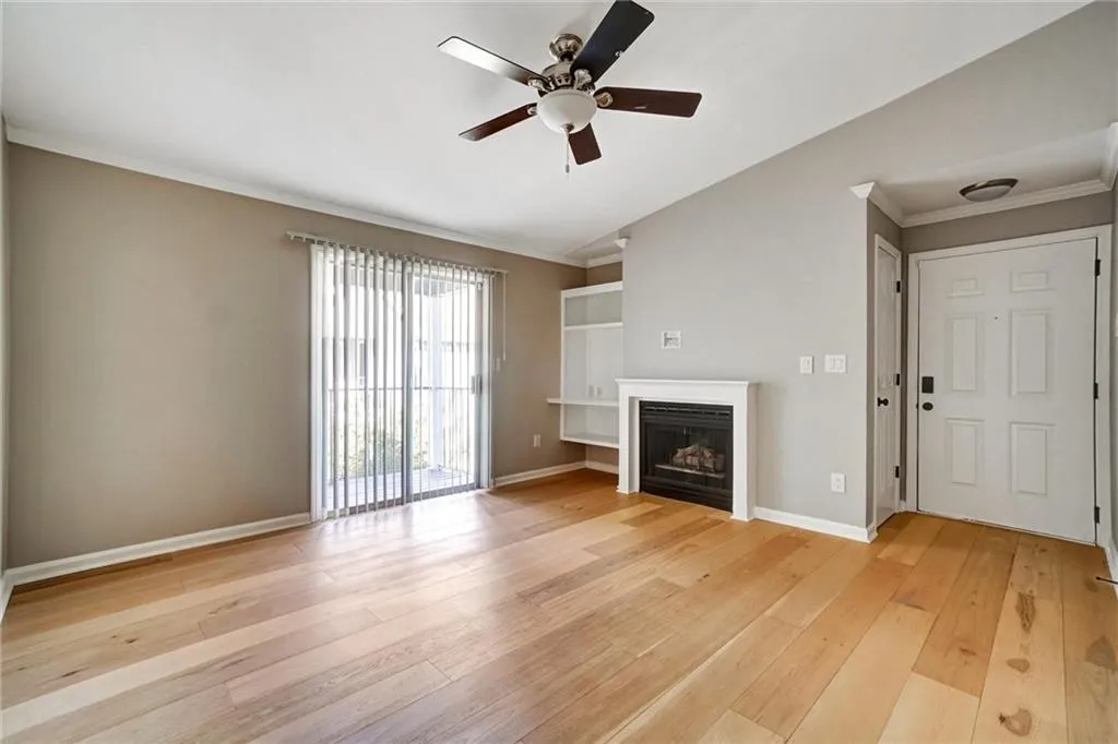 Unfurnished living room with crown molding, light wood-style floors, a fireplace, and a ceiling fan Unfurnished living room with crown molding, light wood-style floors, a fireplace, and a ceiling fan