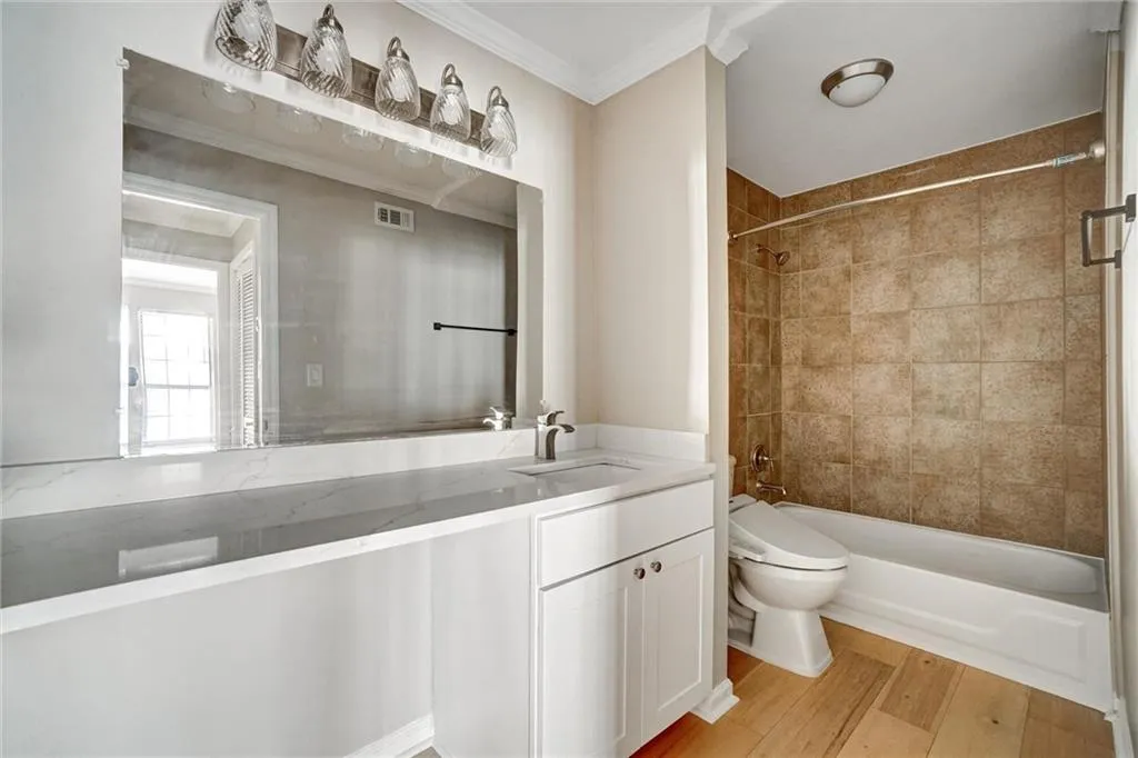 Full bath with light wood-style floors, vanity, shower / bath combination, and crown molding Full bath with light wood-style floors, vanity, shower / bath combination, and crown molding