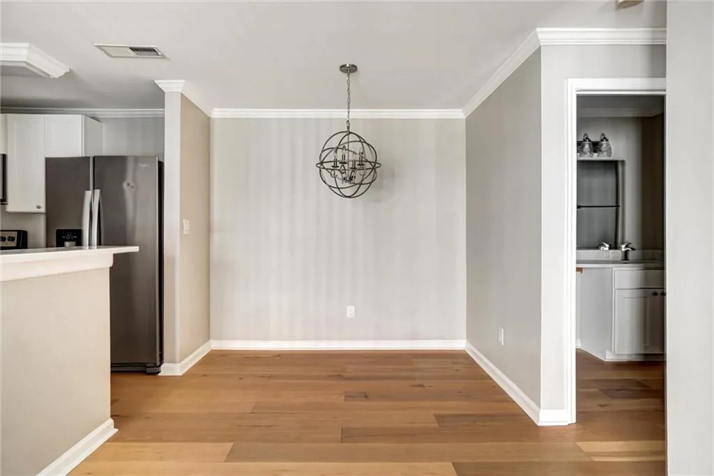 Unfurnished dining area featuring light wood-type flooring, a chandelier, and ornamental molding Unfurnished dining area featuring light wood-type flooring, a chandelier, and ornamental molding