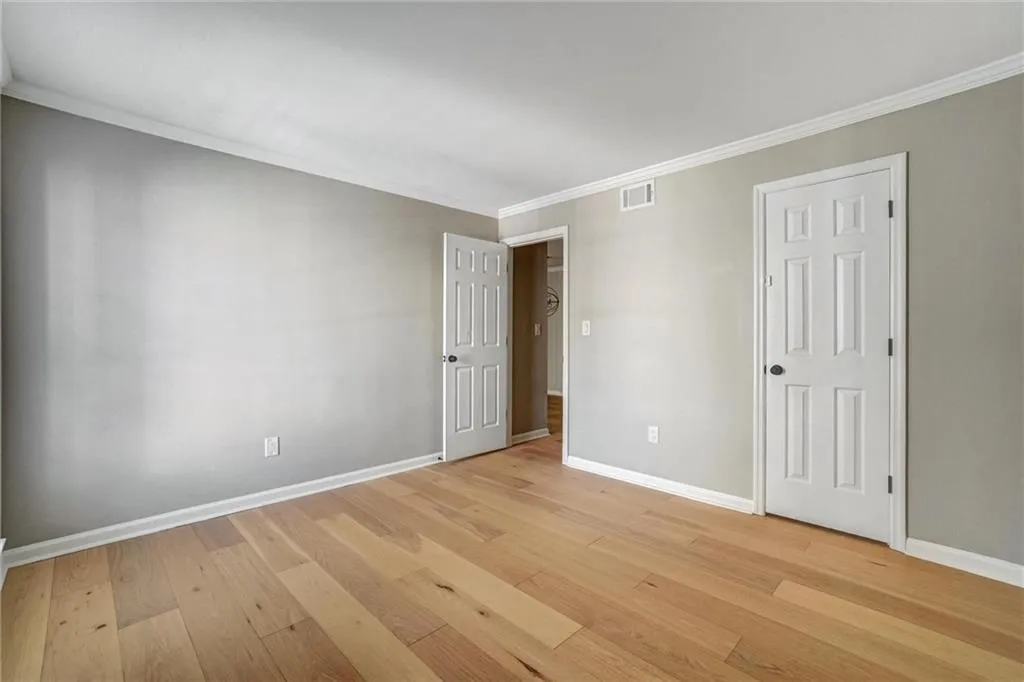 Unfurnished bedroom featuring ornamental molding and light wood-style floors Unfurnished bedroom featuring ornamental molding and light wood-style floors