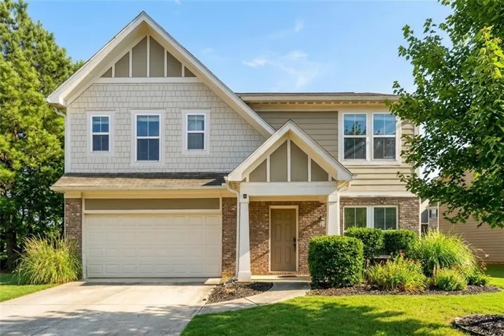 Two-story exterior with a covered entry, brick accents, and a dual-panel garage door