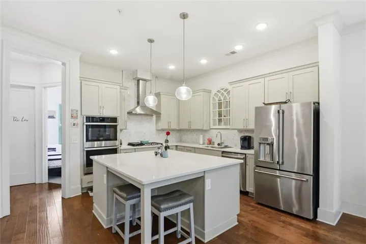 Kitchen featuring a center island with countertop seating, light-toned cabinetry, stainless steel appliances, and wood-finish flooring
