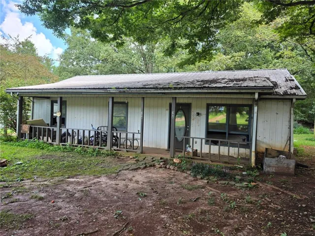 Single-story residence featuring a covered front porch with wood railings and posts, and a metal roof