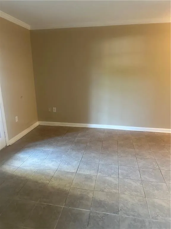 Unfurnished room with crown molding and baseboards