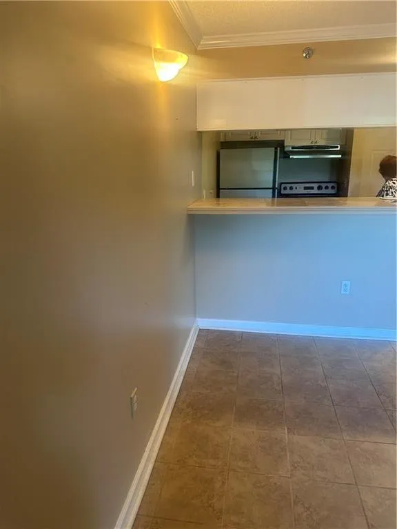 Kitchen with ornamental molding, fridge, a textured ceiling, extractor fan, and tile patterned floors