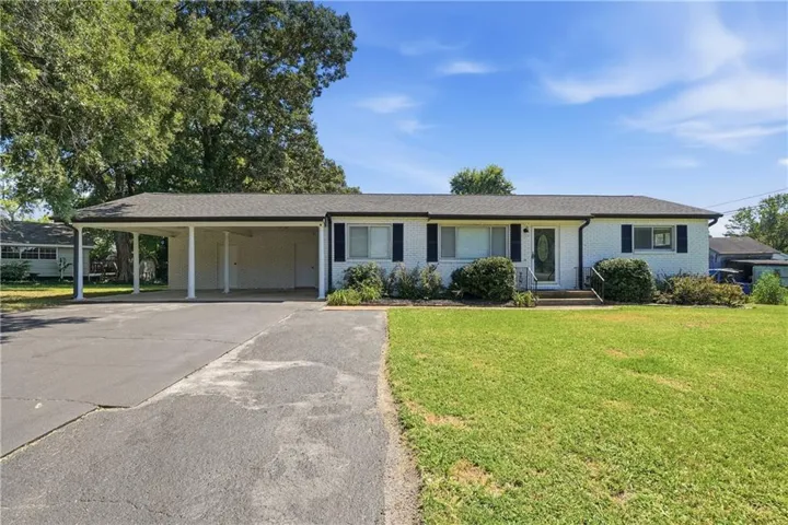 Ranch-style residence featuring a covered carport, paved driveway, and established landscaping