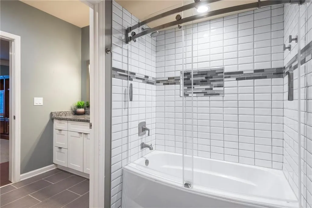 Updated bathroom has beautiful tiles and curved sliding door.