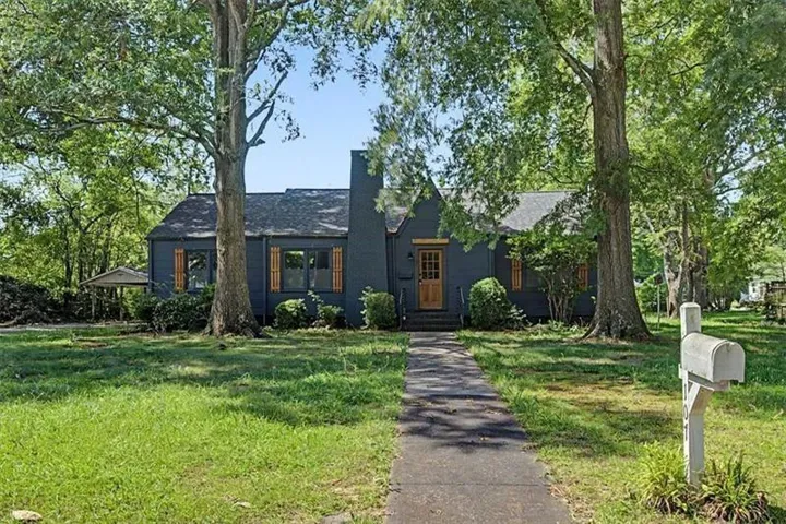 Dark-painted exterior with wood-finish shutters, a wood-panel front door, and a prominent chimney